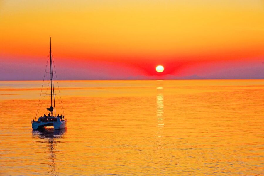 Santorini: Catamaran Tour with BBQ Meal and Unlimited Drinks - Sunset beneath Oia on the evening departure